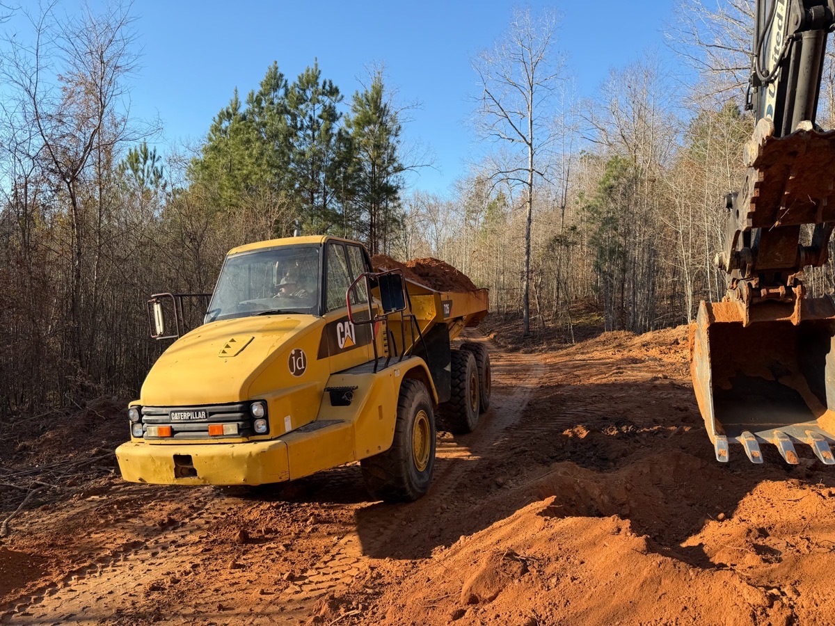 Excavator and forestry mulcher clearing a road through the woods